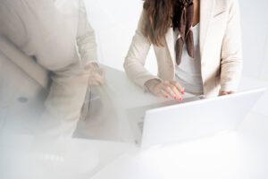 Corporate Fotograf München, Nahaufnahme Schreibtisch mit Laptop und Mitarbeiterinnen
