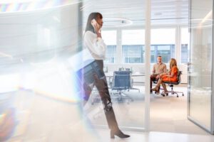 Corporate Fotografie, Besprechungssituation in Bürogebäude, Eine Frau läuft im Vordergrund durch das Bild