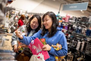 Social Media Fotograf für Store Neueröffnung, zwei Kundinnen schauen sich ein Produkt an und lachen